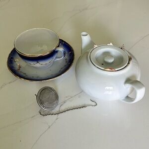 white porcelain teapot and vintage blue and gold teacup with strainer